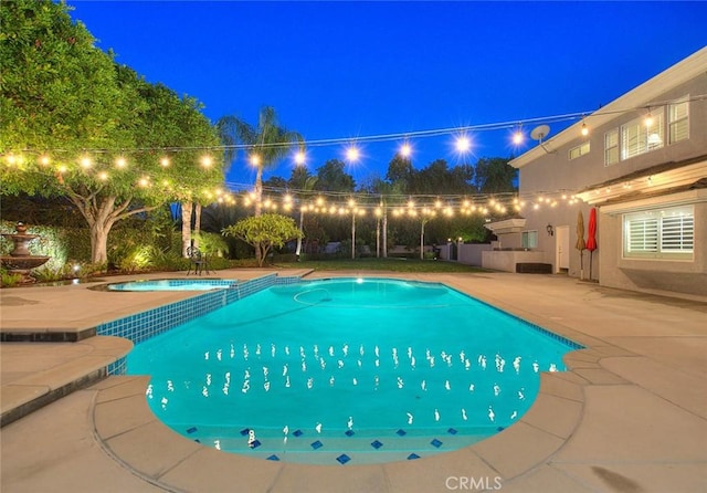 pool at twilight featuring an outdoor kitchen and a patio area