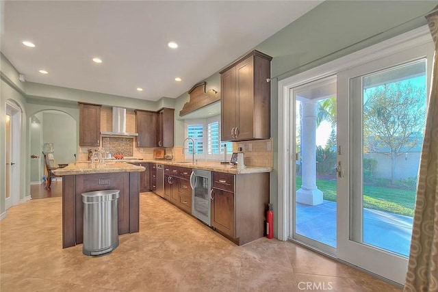 kitchen with tasteful backsplash, sink, a center island, and wall chimney exhaust hood