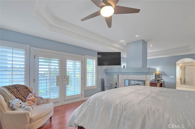 bedroom featuring wood-type flooring, access to outside, ceiling fan, a raised ceiling, and french doors