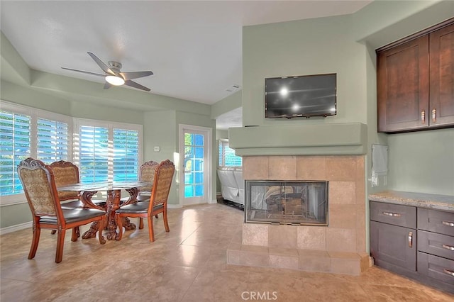 dining space with ceiling fan and a fireplace