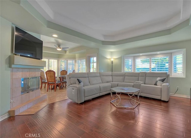 living room featuring a raised ceiling, wood-type flooring, a wealth of natural light, and a fireplace