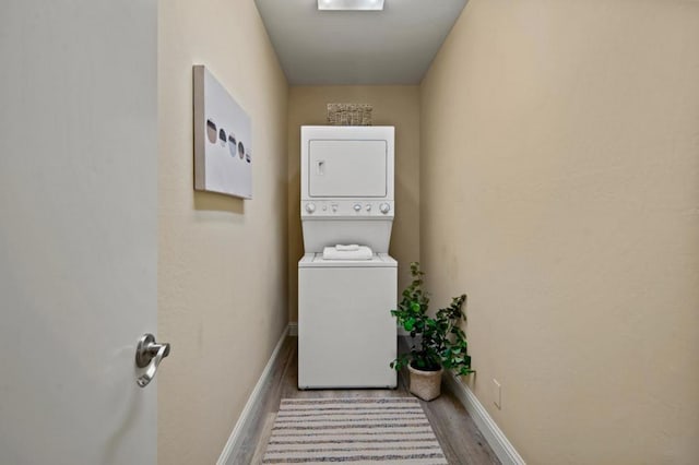 laundry area with light hardwood / wood-style floors and stacked washer and clothes dryer