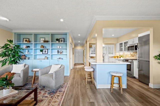 interior space with a breakfast bar, a center island, appliances with stainless steel finishes, light hardwood / wood-style floors, and white cabinets