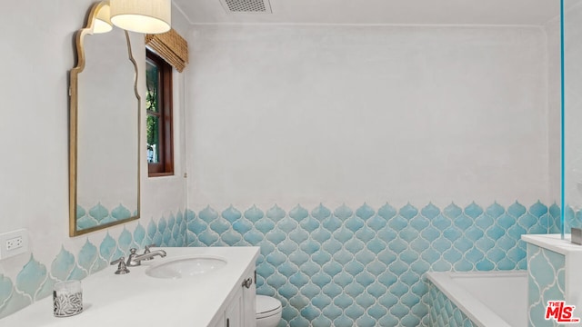 bathroom featuring vanity, a washtub, and toilet