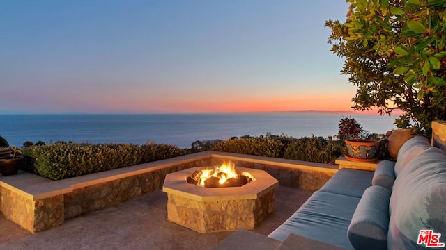 patio terrace at dusk with a water view and an outdoor living space with a fire pit