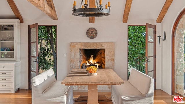 dining area featuring beamed ceiling, a high end fireplace, a chandelier, and light hardwood / wood-style floors