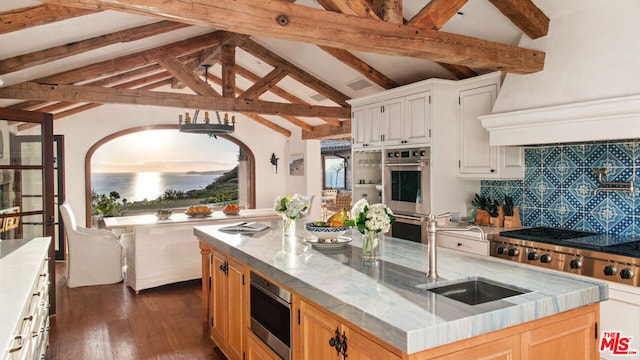 kitchen with sink, white cabinetry, appliances with stainless steel finishes, dark hardwood / wood-style flooring, and a kitchen island with sink