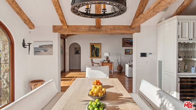 dining area featuring wine cooler, indoor bar, hardwood / wood-style floors, and beamed ceiling