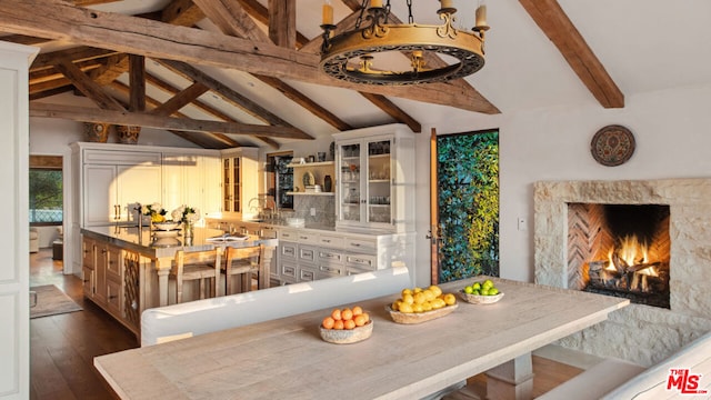 dining space with a high end fireplace, dark hardwood / wood-style floors, and lofted ceiling with beams