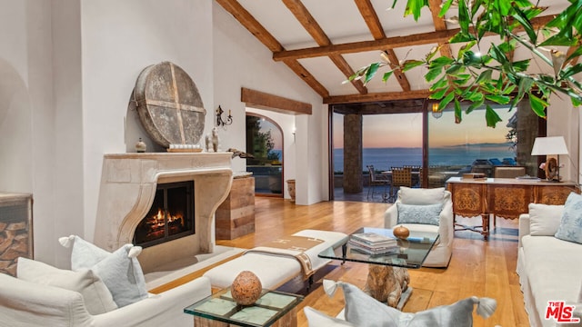 living room with high vaulted ceiling, a premium fireplace, beam ceiling, and light hardwood / wood-style flooring