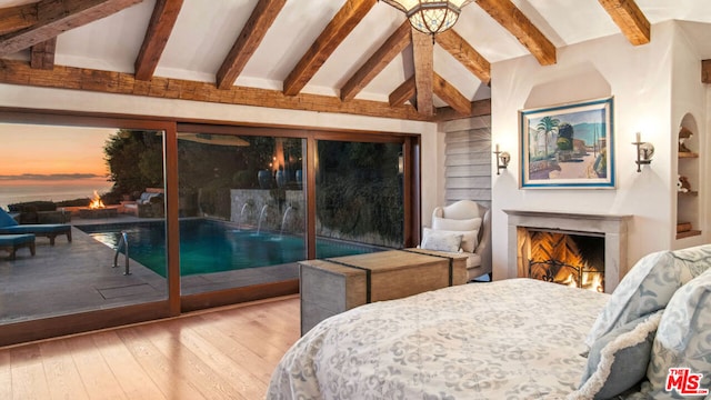 bedroom with wood-type flooring, beamed ceiling, and access to outside