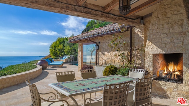 view of patio / terrace with a water view and an outdoor stone fireplace