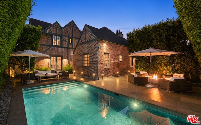 pool at dusk featuring french doors, an outdoor living space, and a patio