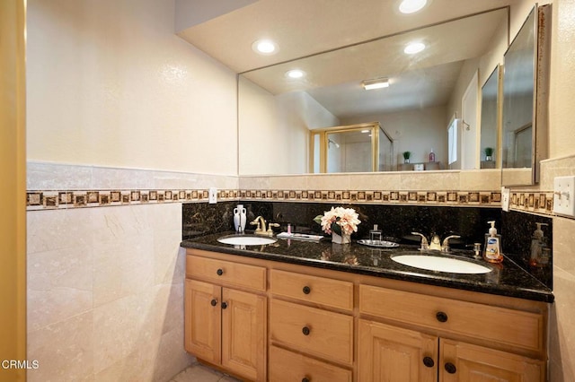 bathroom with walk in shower, vanity, and tile walls