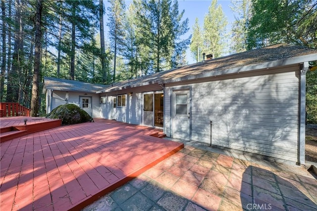 rear view of property featuring a wooden deck, a jacuzzi, and a patio