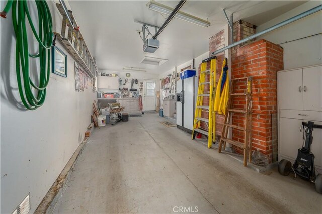 garage with a garage door opener and white refrigerator with ice dispenser