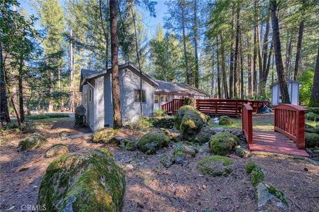 view of property exterior featuring a wooden deck and a shed