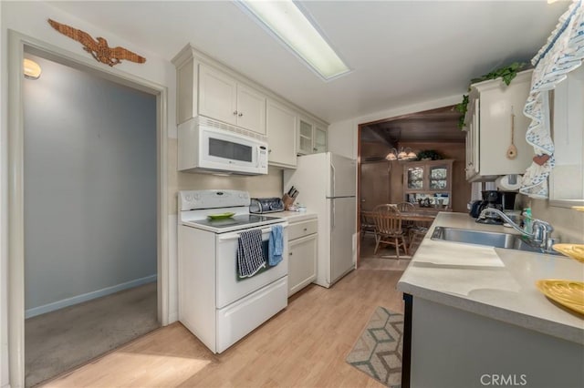 kitchen with white cabinetry, sink, white appliances, and light hardwood / wood-style flooring