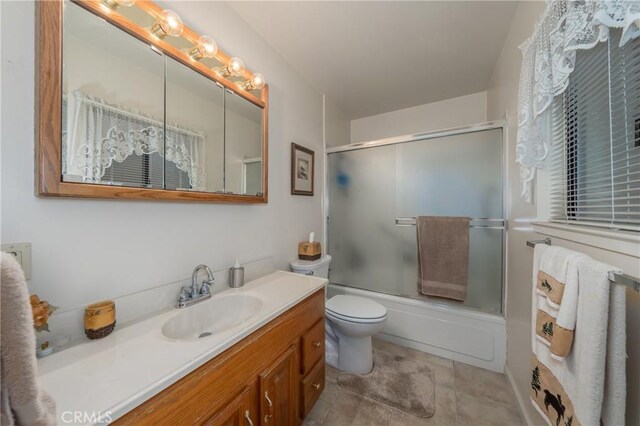 full bathroom featuring vanity, bath / shower combo with glass door, and toilet