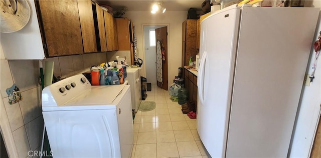 laundry room with independent washer and dryer, cabinets, and light tile patterned floors