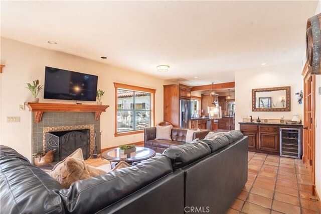 living room with bar, a tile fireplace, light tile patterned flooring, and wine cooler