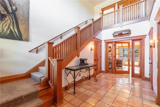 stairs featuring a towering ceiling and tile patterned flooring