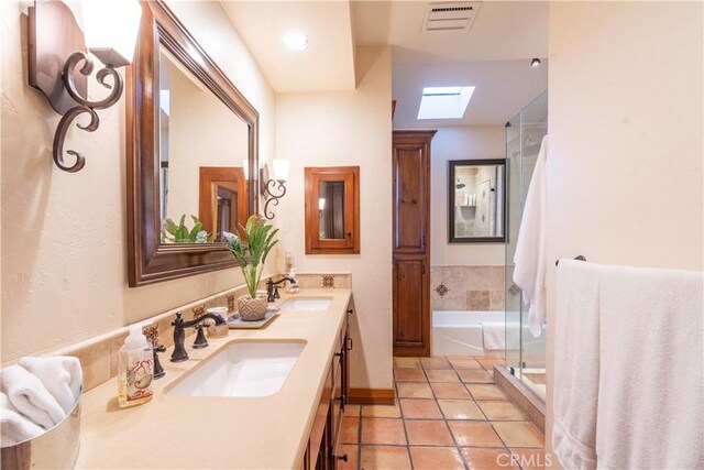 bathroom with vanity, tile patterned flooring, a skylight, and separate shower and tub