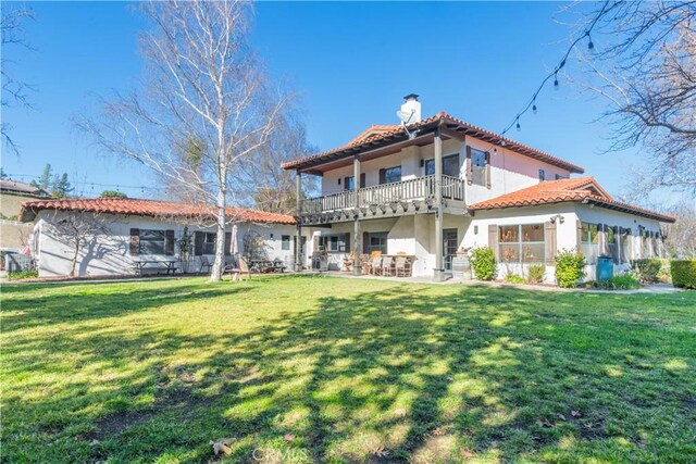 back of property with a balcony and a lawn