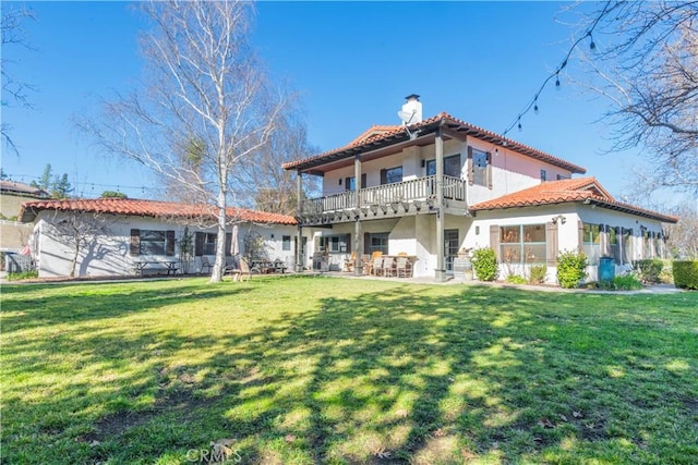 rear view of property featuring a yard and a balcony