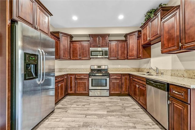 kitchen featuring sink, light hardwood / wood-style flooring, light stone countertops, and appliances with stainless steel finishes