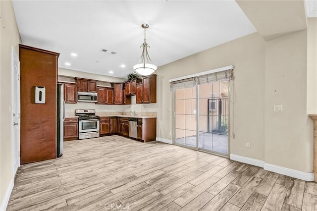 kitchen with sink, appliances with stainless steel finishes, decorative light fixtures, and light hardwood / wood-style floors