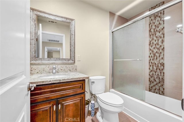 full bathroom featuring vanity, bath / shower combo with glass door, and toilet