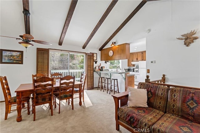 carpeted dining area featuring beamed ceiling, ceiling fan, sink, and high vaulted ceiling