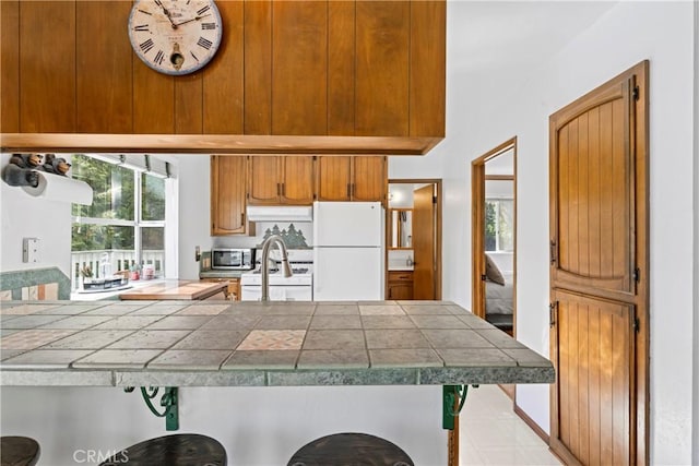 kitchen featuring tile counters, white appliances, and kitchen peninsula