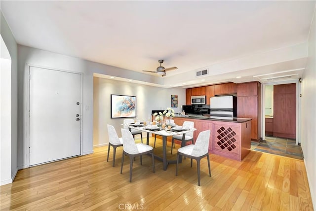 dining space with ceiling fan and light hardwood / wood-style flooring