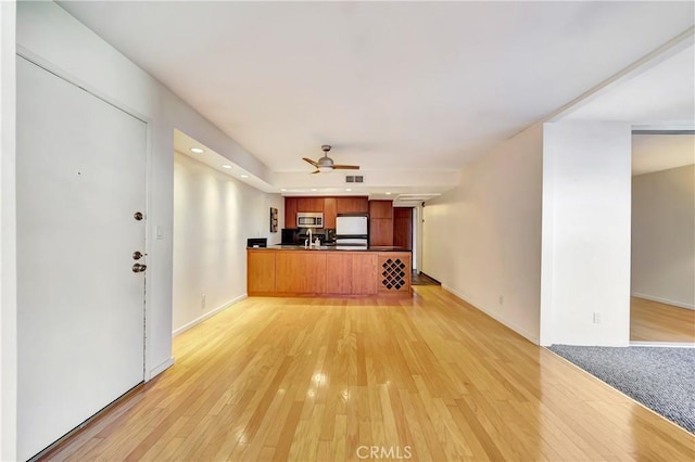 unfurnished living room featuring ceiling fan and light hardwood / wood-style floors