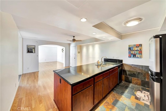 kitchen featuring sink, light hardwood / wood-style flooring, appliances with stainless steel finishes, kitchen peninsula, and ceiling fan