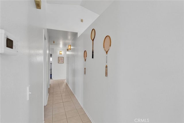 hall with lofted ceiling and light tile patterned floors