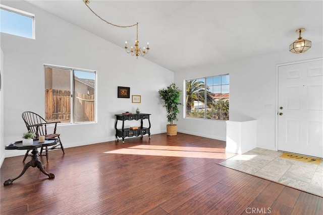 foyer featuring a notable chandelier, a wealth of natural light, wood-type flooring, and high vaulted ceiling