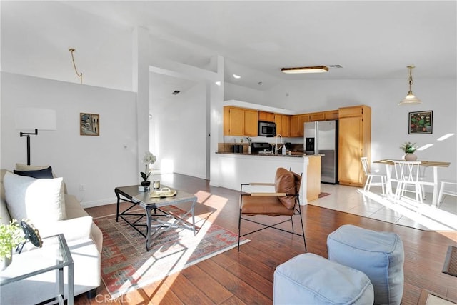 living room featuring high vaulted ceiling and light hardwood / wood-style flooring