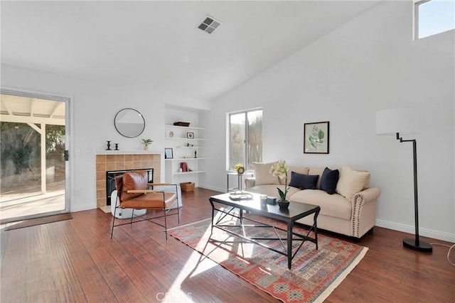 living room with a fireplace, dark wood-type flooring, built in features, and high vaulted ceiling