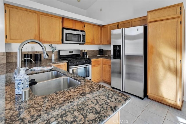 kitchen featuring light tile patterned flooring, appliances with stainless steel finishes, sink, and dark stone countertops