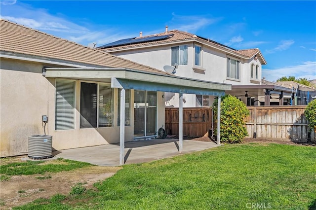 back of house with central AC unit, a yard, a patio area, and solar panels