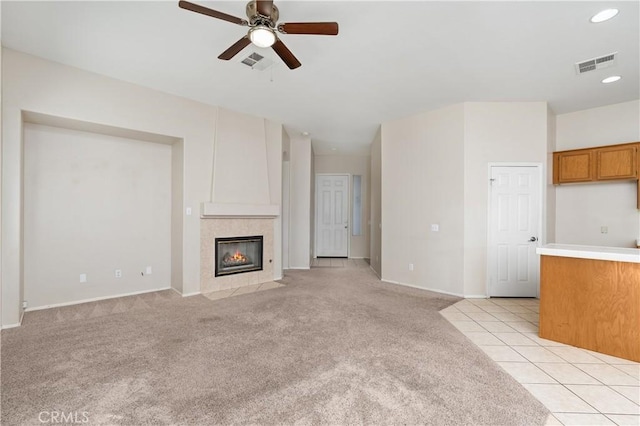 unfurnished living room with ceiling fan, light colored carpet, and a fireplace