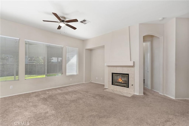 unfurnished living room featuring a tile fireplace, light colored carpet, and ceiling fan