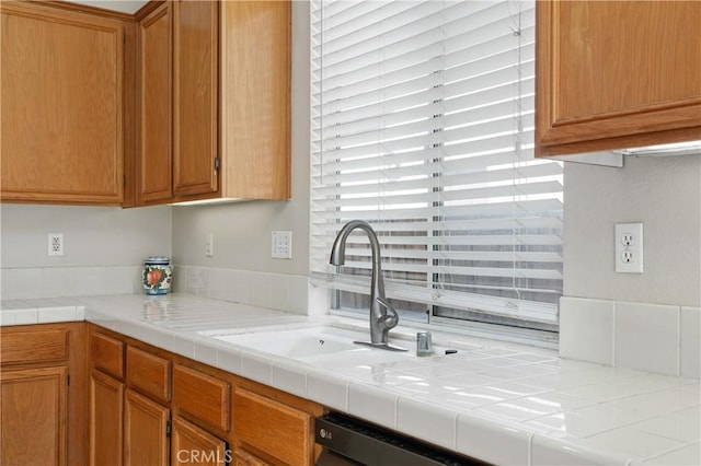 kitchen with tile counters, dishwasher, and sink