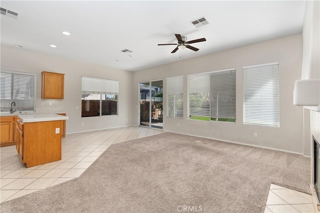 unfurnished living room with ceiling fan, light colored carpet, and sink