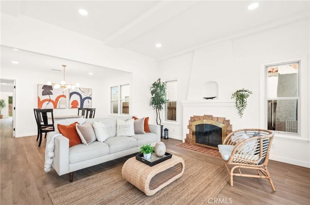 living room with beam ceiling, wood-type flooring, plenty of natural light, and an inviting chandelier