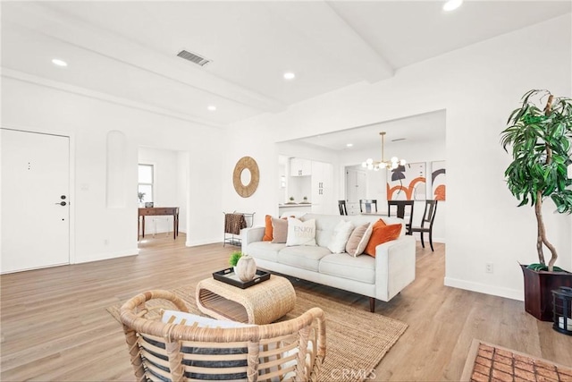 living room featuring beamed ceiling, an inviting chandelier, and light hardwood / wood-style flooring