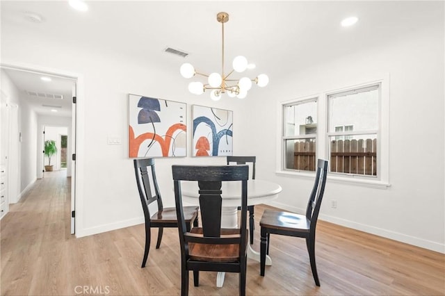 dining area featuring light hardwood / wood-style flooring and a notable chandelier